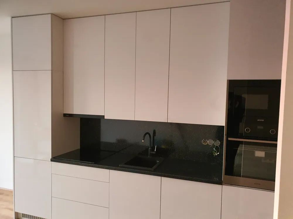 Bílá vysoká lesklá sestava s&nbsp;černou deskou a&nbsp;troubou ve výšce očí