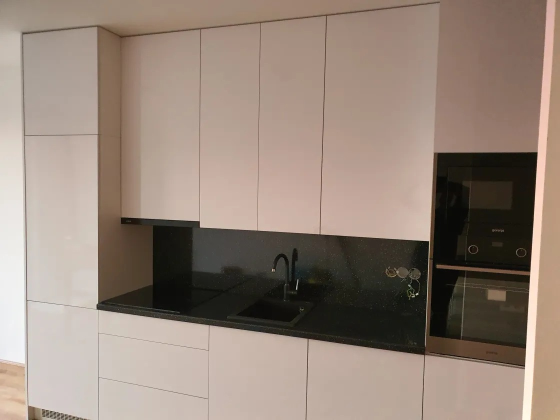 Bílá vysoká lesklá sestava s&nbsp;černou deskou a&nbsp;troubou ve výšce očí