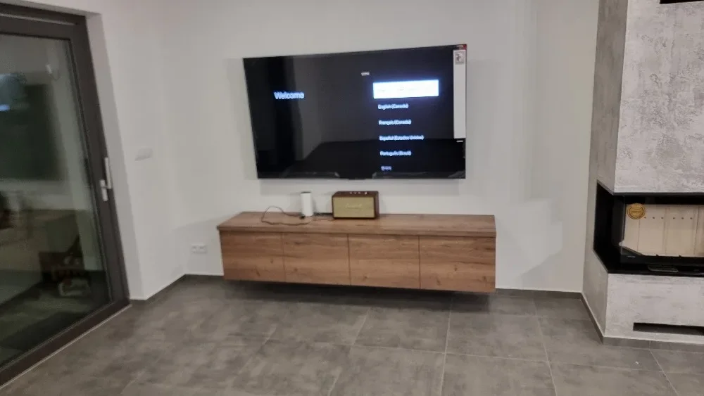 Dubová závěsná TV komoda pod televizí vedle krbu