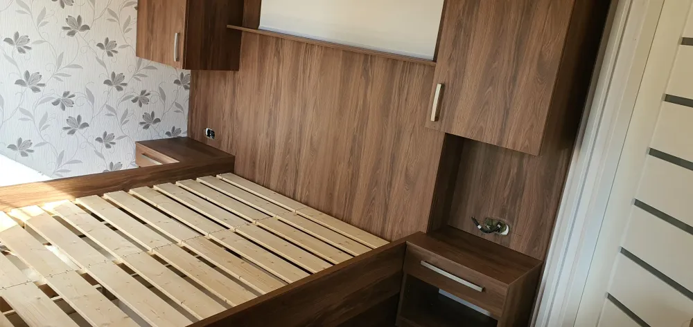 Postel v&nbsp;dekoru ořechu se zabudovaným čelem a&nbsp;nočními stolky