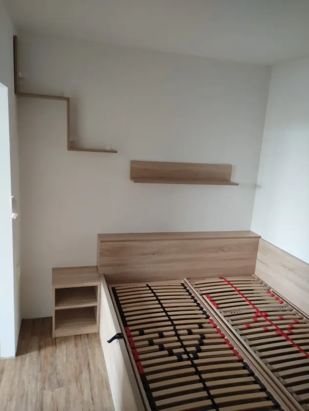 Manželská postel v&nbsp;dekoru dubu s&nbsp;čelem, nočním stolkem a&nbsp;policemi na stěně
