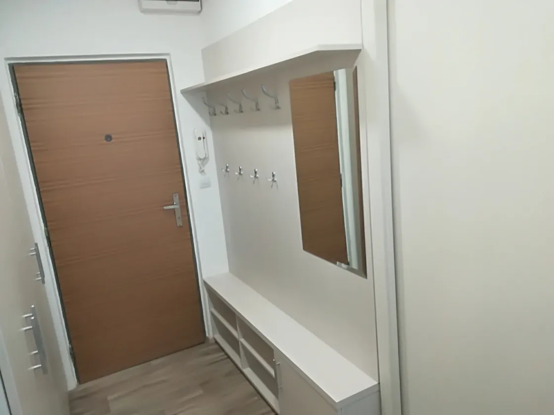 Bílá předsíňová stěna se zrcadlem, věšáky a&nbsp;otevřeným botníkem