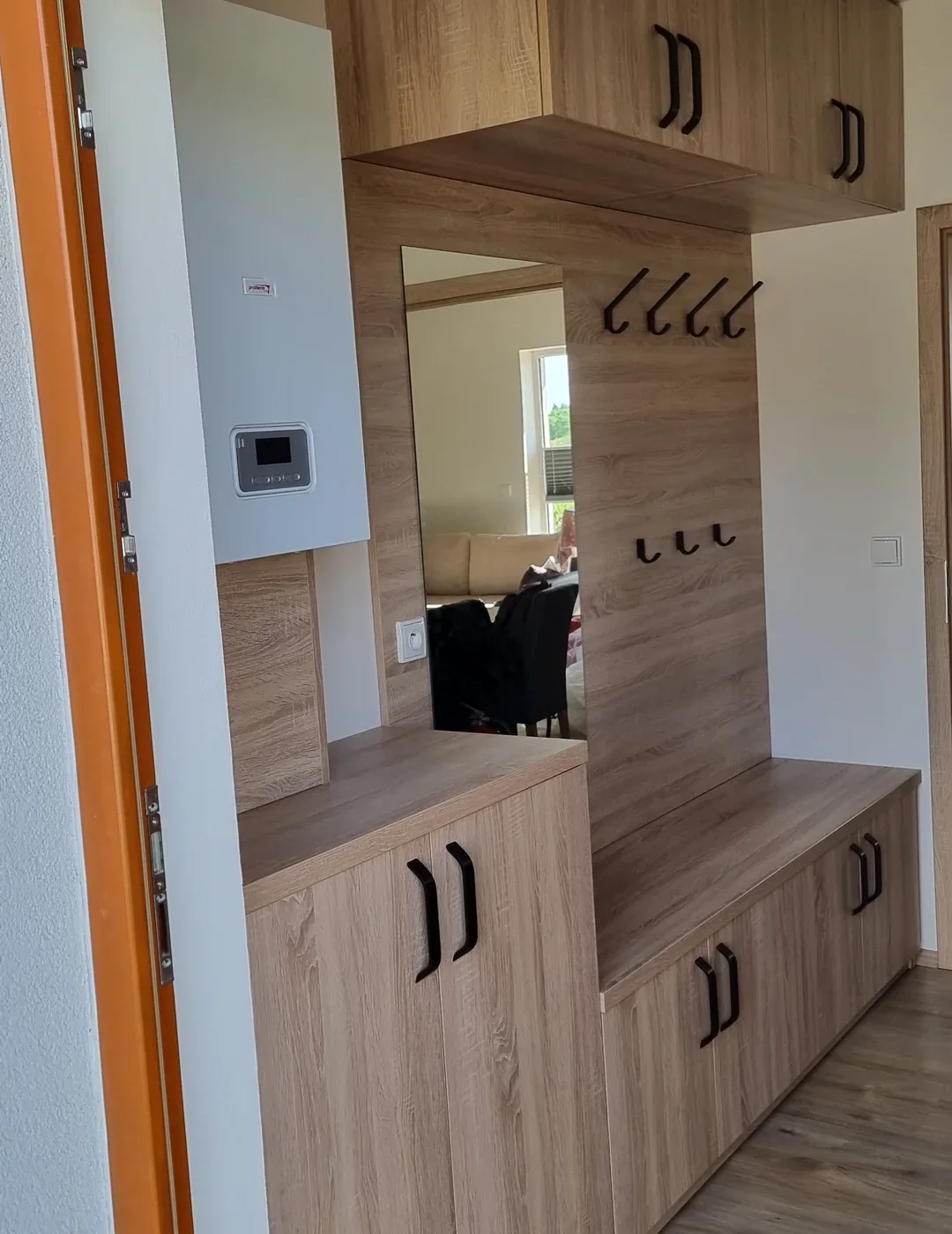 Předsíň v&nbsp;dubovém dekoru se zrcadlem, věšáky, lavicí a&nbsp;skříňkami pod ní