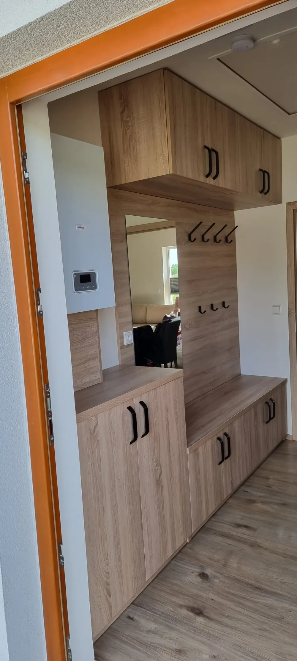 Předsíň v&nbsp;dubovém dekoru se zrcadlem, věšáky, lavicí a&nbsp;skříňkami pod ní