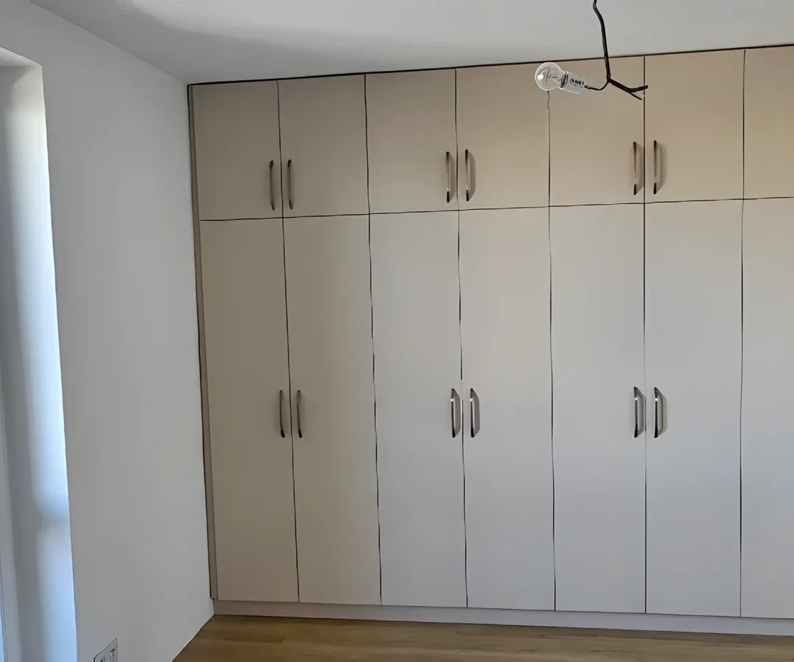 Světlá šatní stěna s&nbsp;dvaceti dvířky přes celou místnost