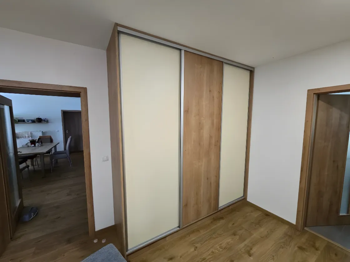 Posuvná skříň s&nbsp;bílými a&nbsp;dubovými panely mezi dvěma dveřmi