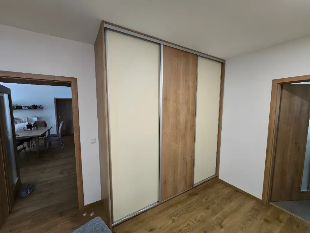 Posuvná skříň s&nbsp;bílými a&nbsp;dubovými panely mezi dvěma dveřmi