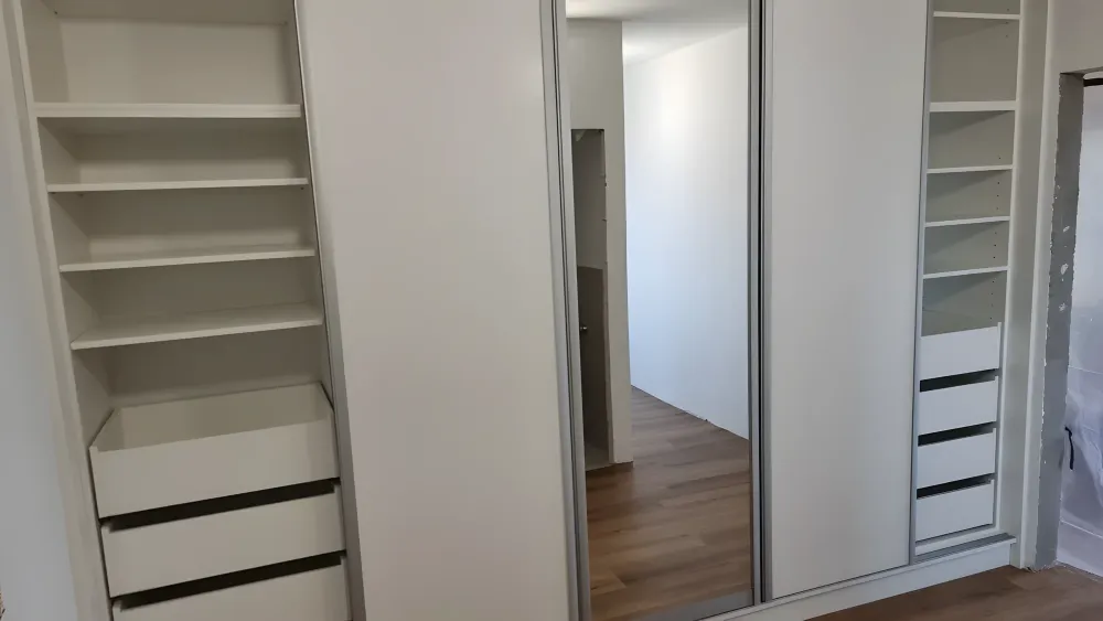 Otevřené police a&nbsp;zásuvky za posuvnými dveřmi se zrcadlem